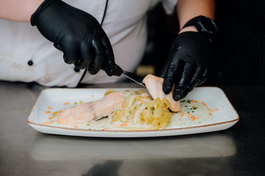 Lachs wird zu den Nudeln auf den Teller gelegt