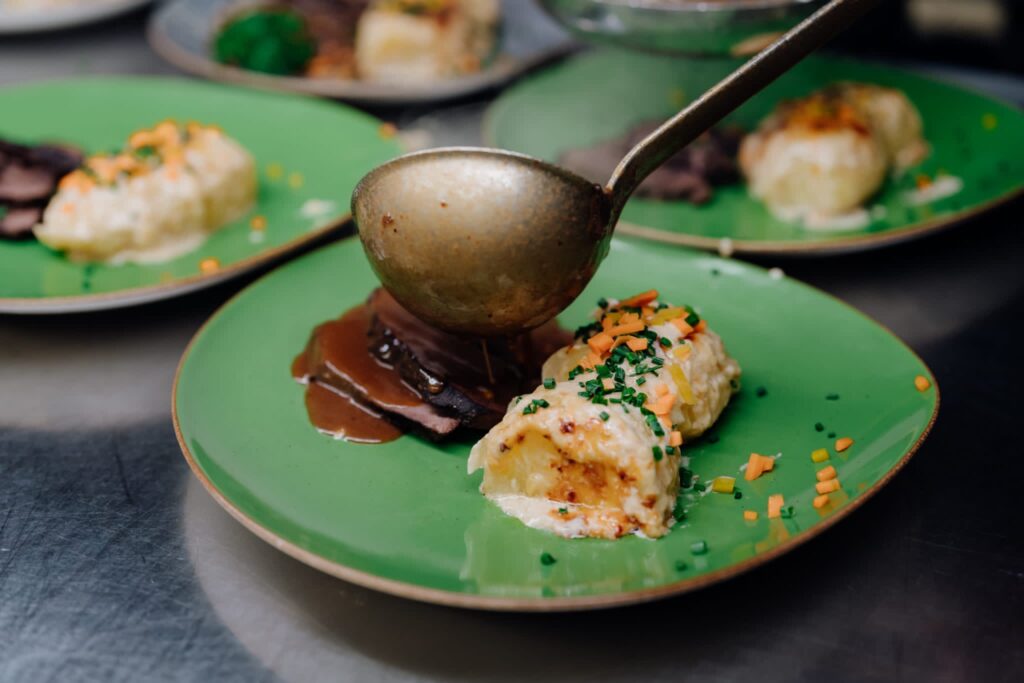 Soße wird mit Kelle auf Teller gegossen