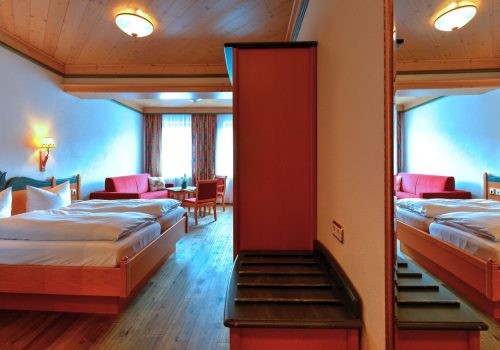 Zimmer mit Bett und Sitzmöglichkeiten, welche auch im Spiegel zu sehen sind